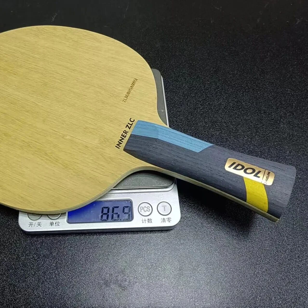 Zhuolong IDOL INNER ZLC blade on a digital scale reading 86.9g, showing the colorful carbon handle