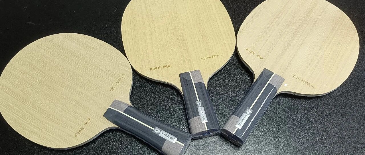 Three Yinhe table tennis blades displayed on a black surface