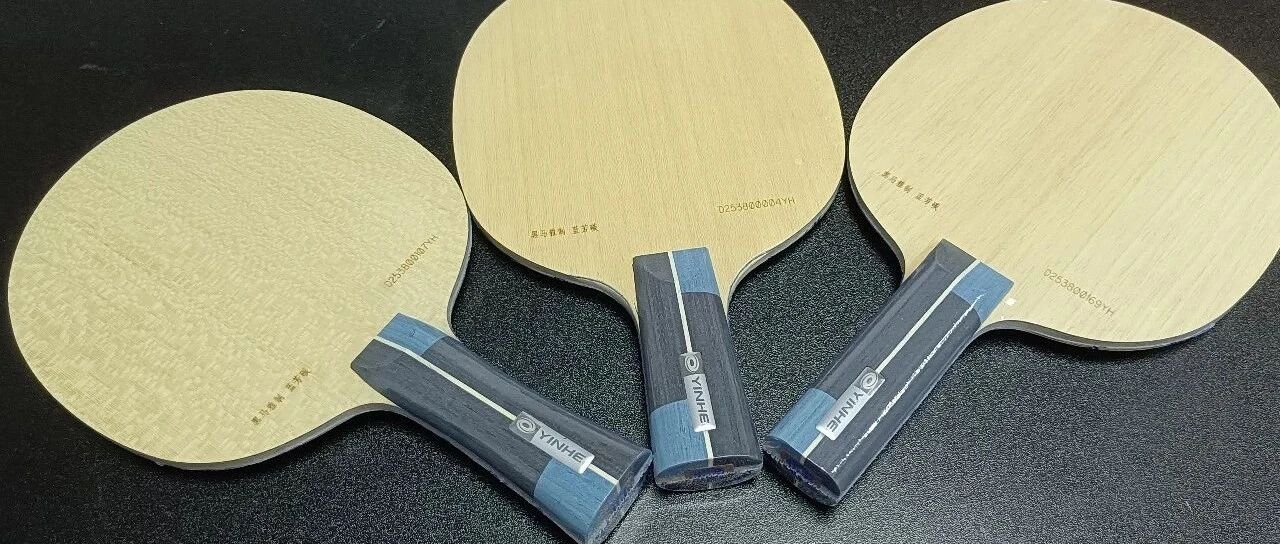 Three Yinhe table tennis blades displayed on a dark surface