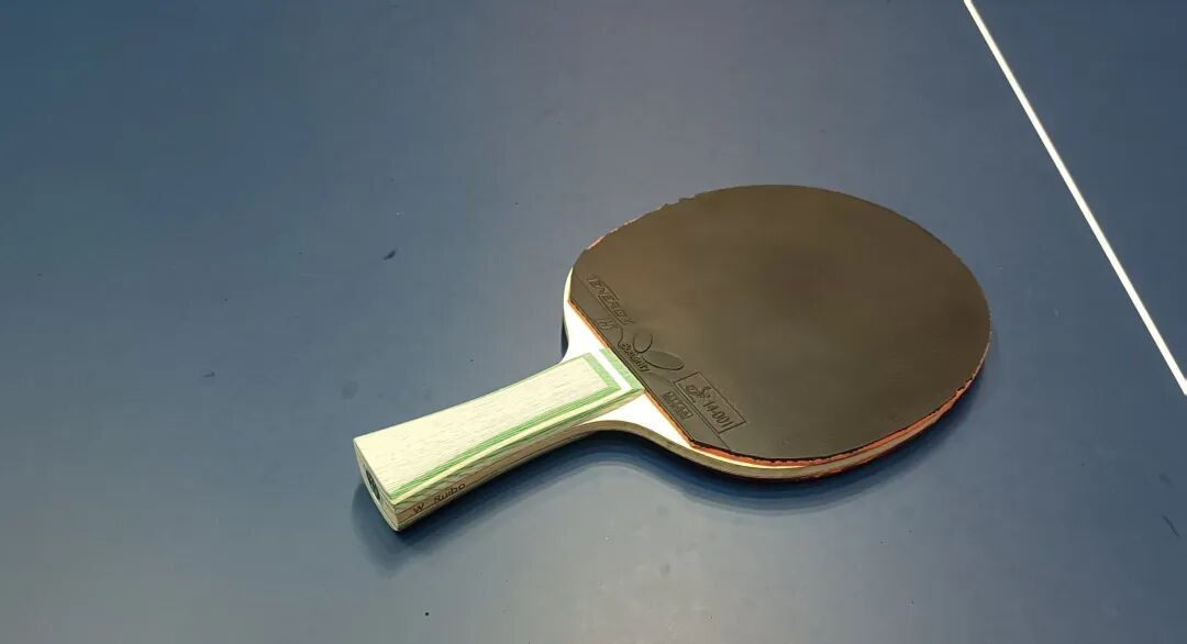 Table tennis racket with penhold grip on a blue table