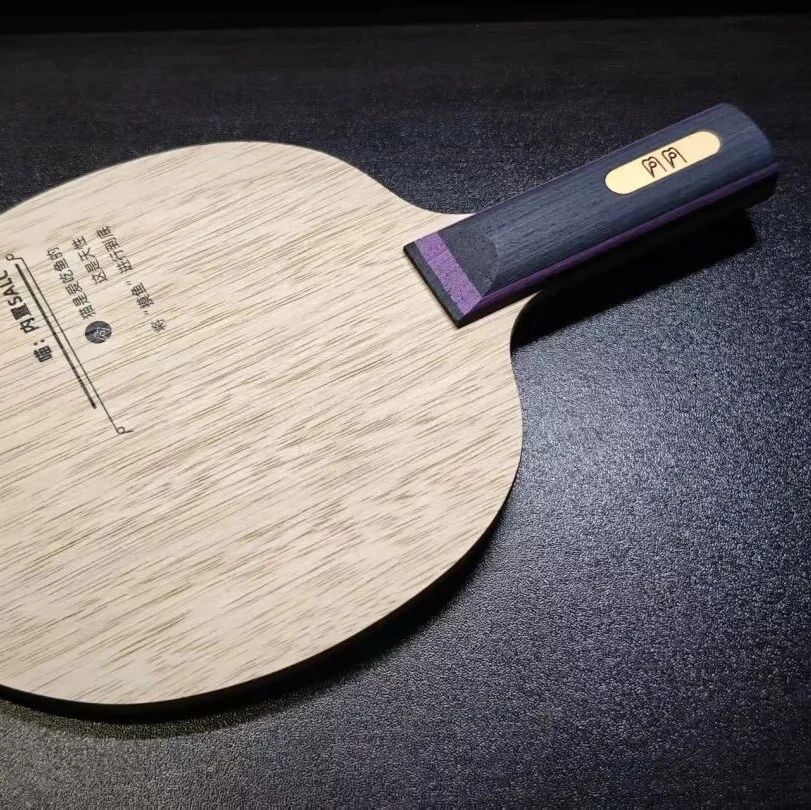 A table tennis blade photographed on a dark surface