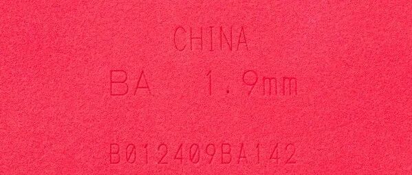 Close-up of a red rubber sponge with CHINA and size markings embossed, illustrating a modified special-edition sponge