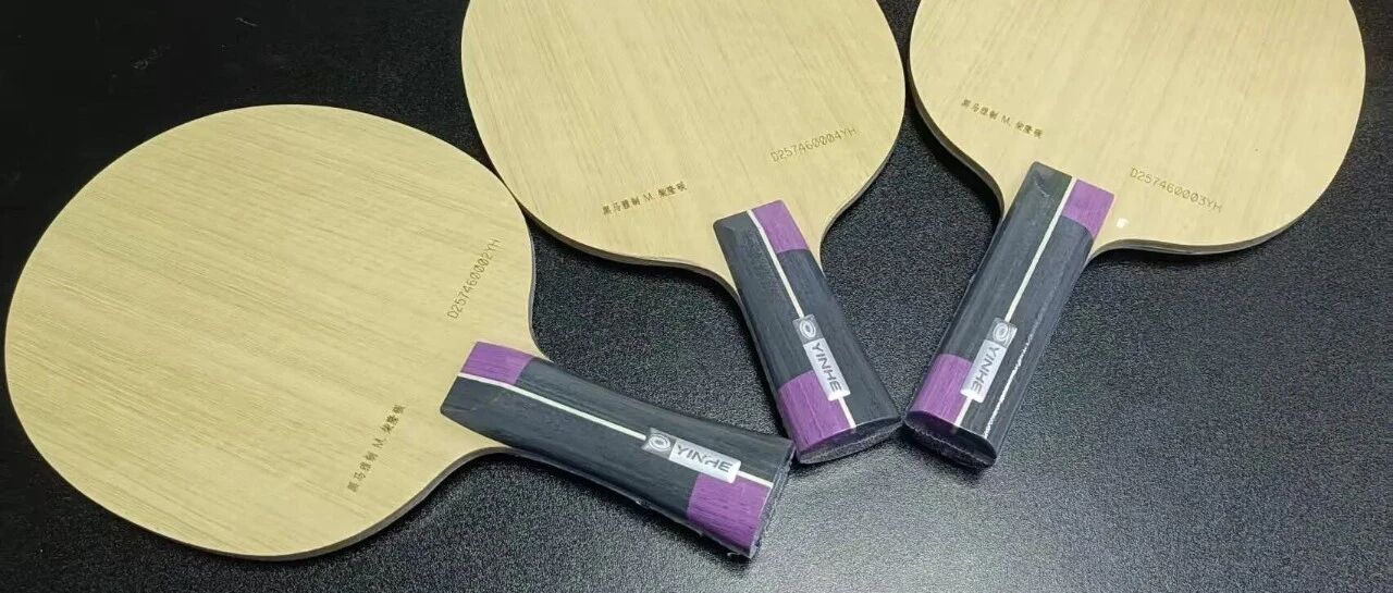 Two Yinhe custom shakehand blades with blue handles resting face-up on a dark surface