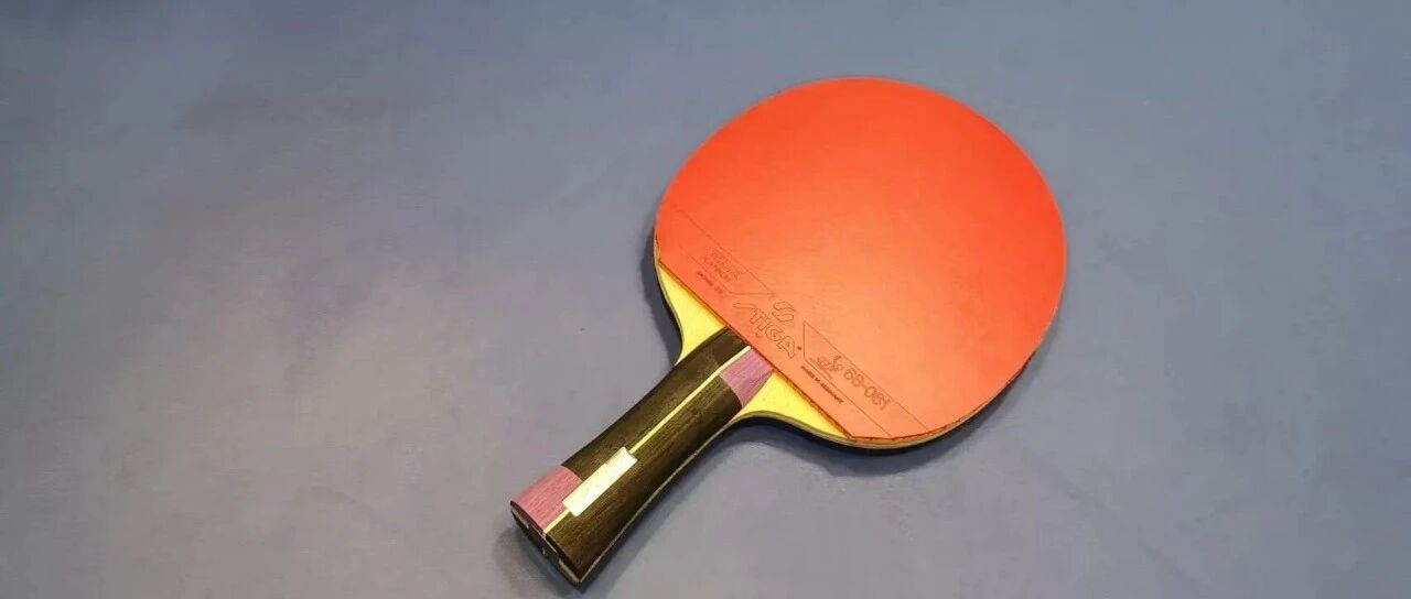 Table tennis paddle with red rubber lying on a blue table near the net