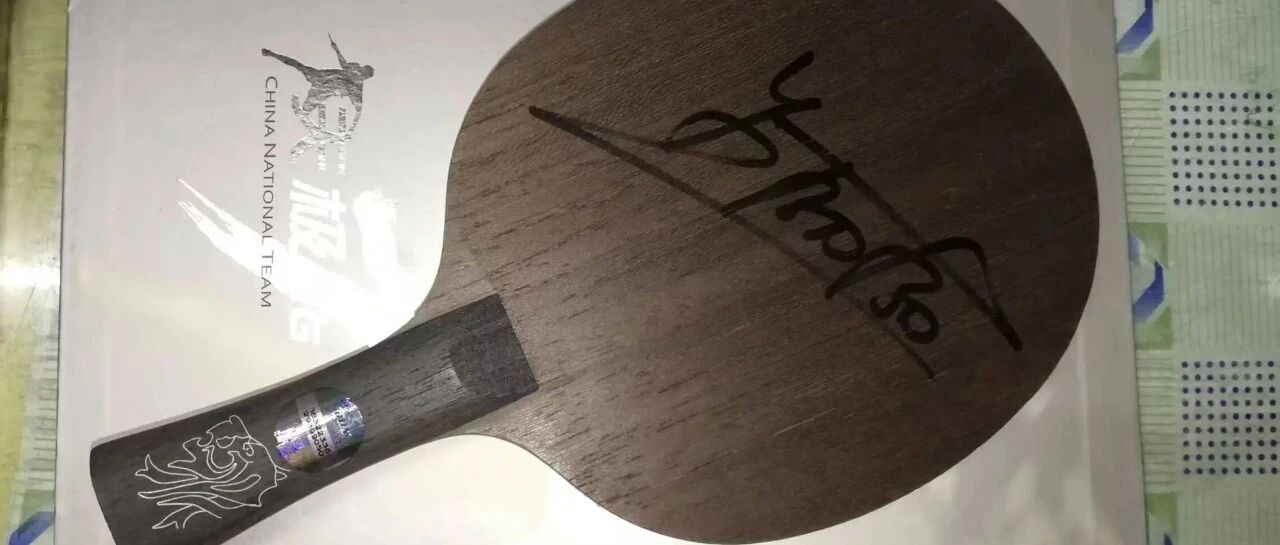 A dark walnut-grained penhold blade with signature, placed on the China National Team packaging box