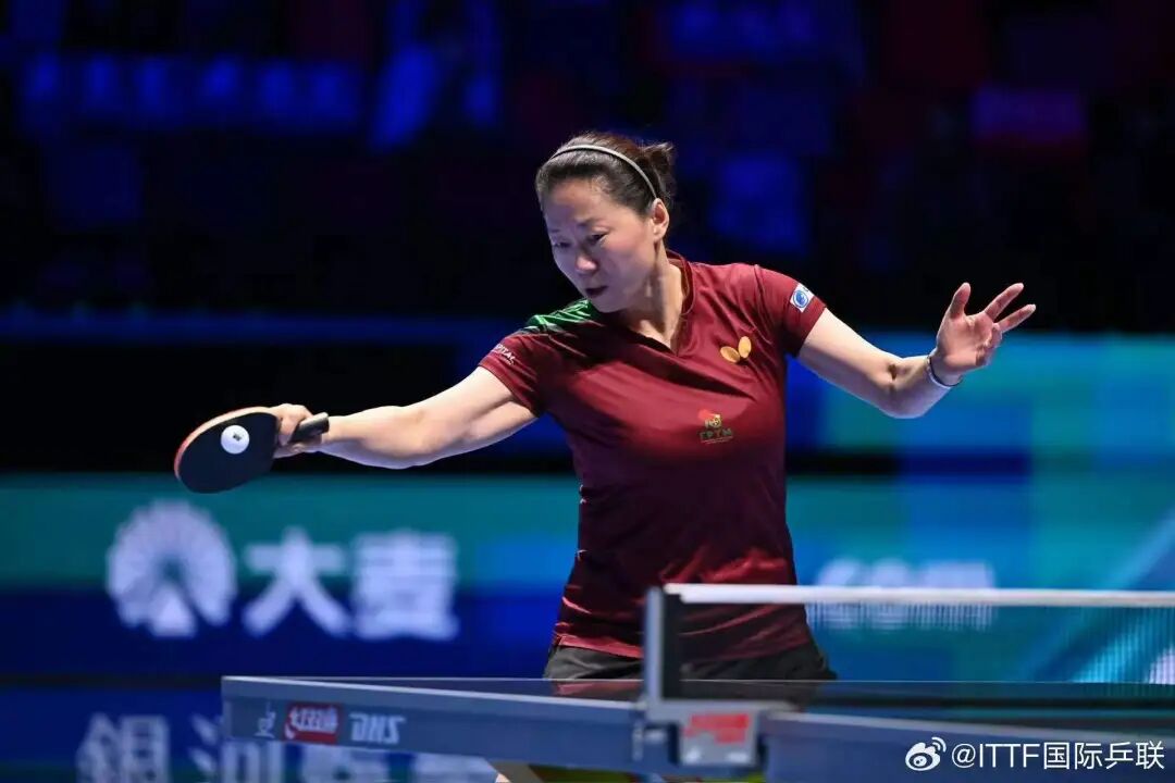 Fu Yu, 47-year-old Portuguese veteran, serving with high-toss against Wang Manyu