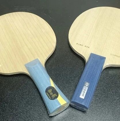 Two Yinhe table tennis blades side by side on a dark surface
