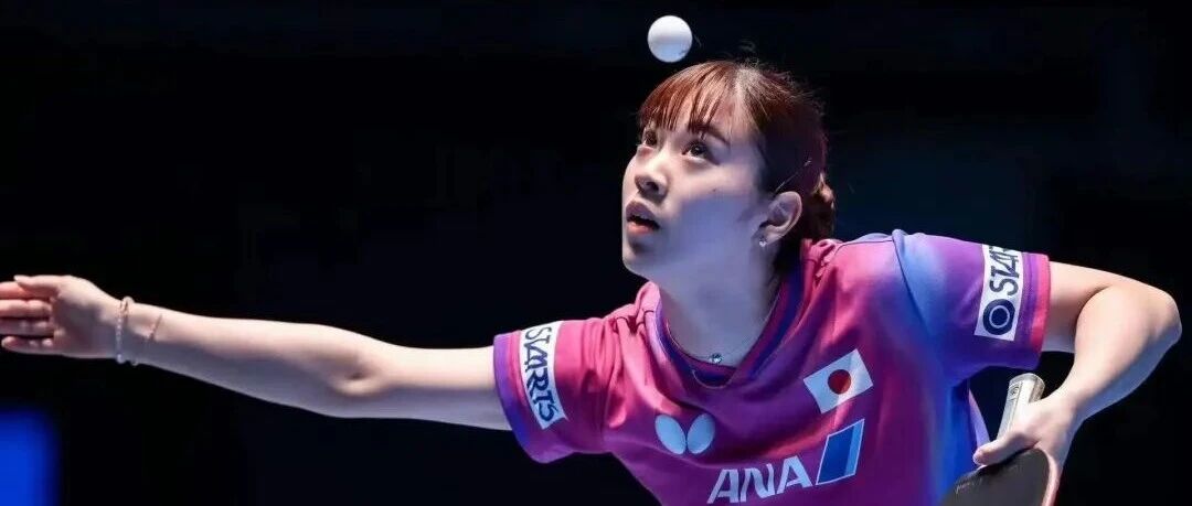 Japanese female table tennis player mid-serve at a competitive match