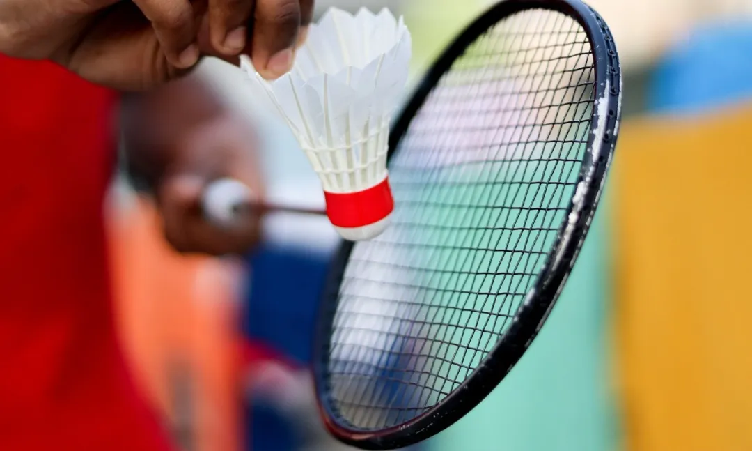 A player holding a badminton racket and shuttlecock, illustrating sports safety discussion