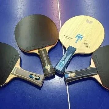 Four table tennis paddles laid out on a blue court surface