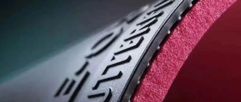 Close-up macro shot of a tacky rubber sheet edge showing the pimple layer in deep red sponge