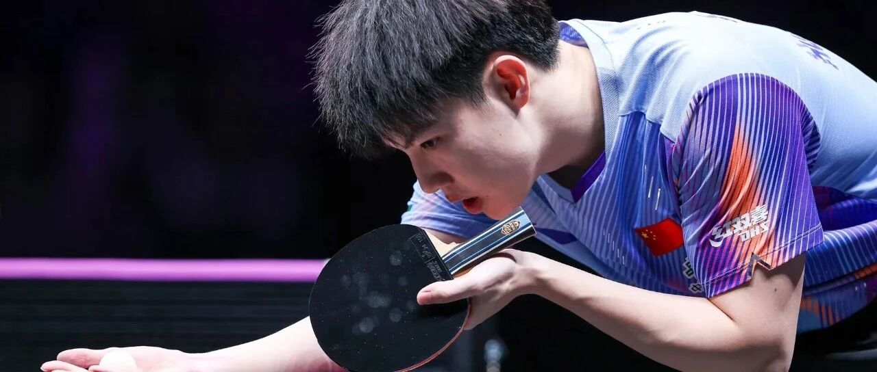 Zhou Qihao leaning in to serve close to the table at a WTT event