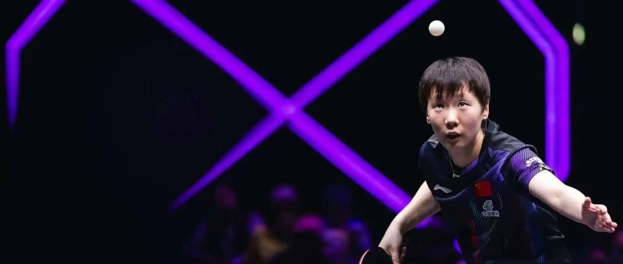 Wang Manyu serving at a WTT event under dramatic purple stage lighting