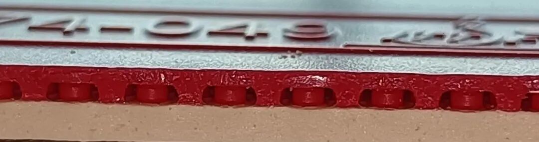 Close-up of thin elongated rubber pips showing soft deformable topsheet structure