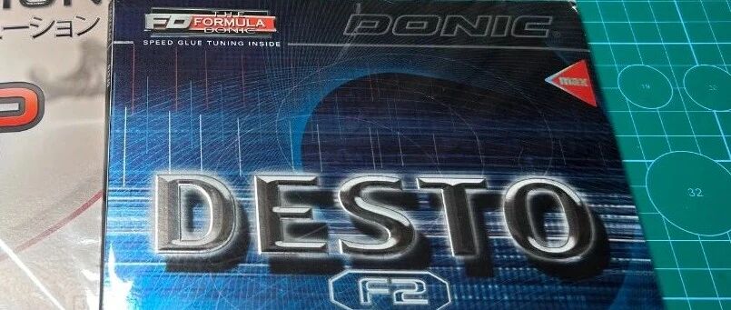 Donic Desto F2 rubber packaging box on a cutting mat next to a Tibhar Evolution MXP box