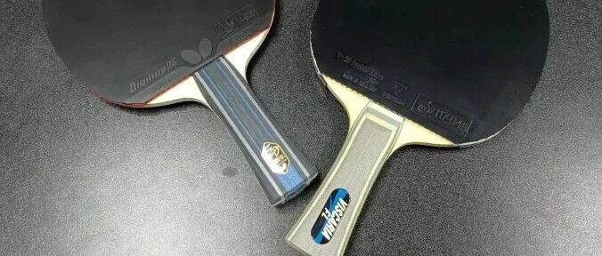 Two Butterfly blades with black Dignics rubber side by side on a dark surface