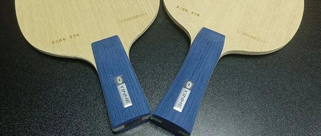 Two Yinhe Galaxy table tennis blades with blue handles on a dark background