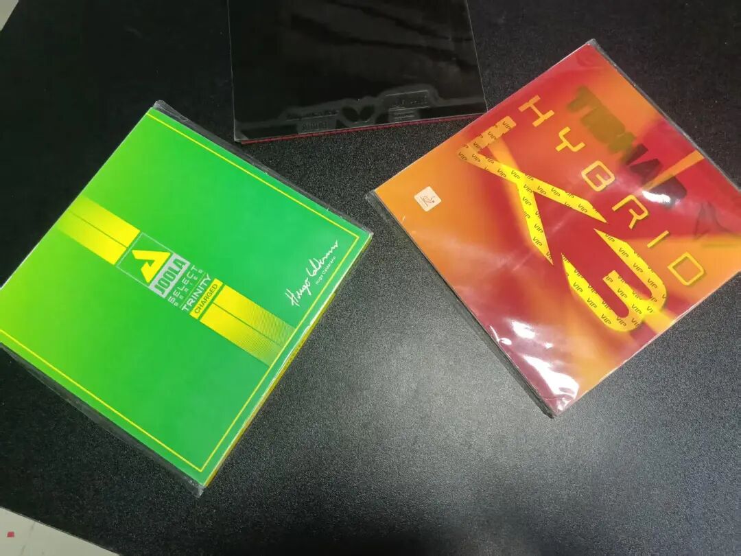 JOOLA Trinity Charged and Hybrid K3 Pro rubber packages side by side on a dark surface