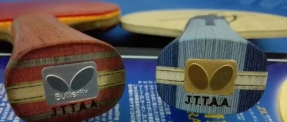 Close-up of two vintage Butterfly blade end-caps showing the old and newer logo designs