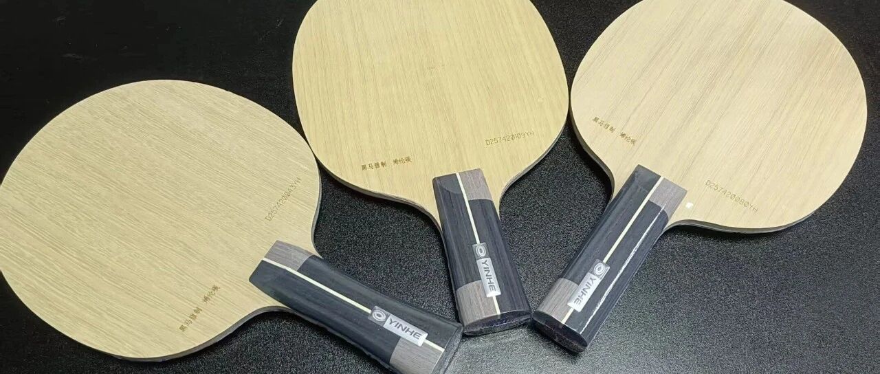 Three Yinhe custom table tennis blades displayed on a black surface showing the face and handle