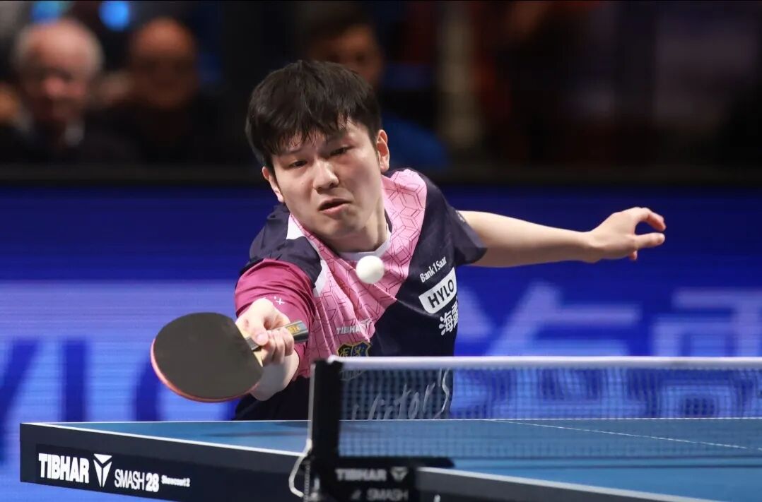 Fan Zhendong in match action at a European Champions League event, stretching for a forehand loop