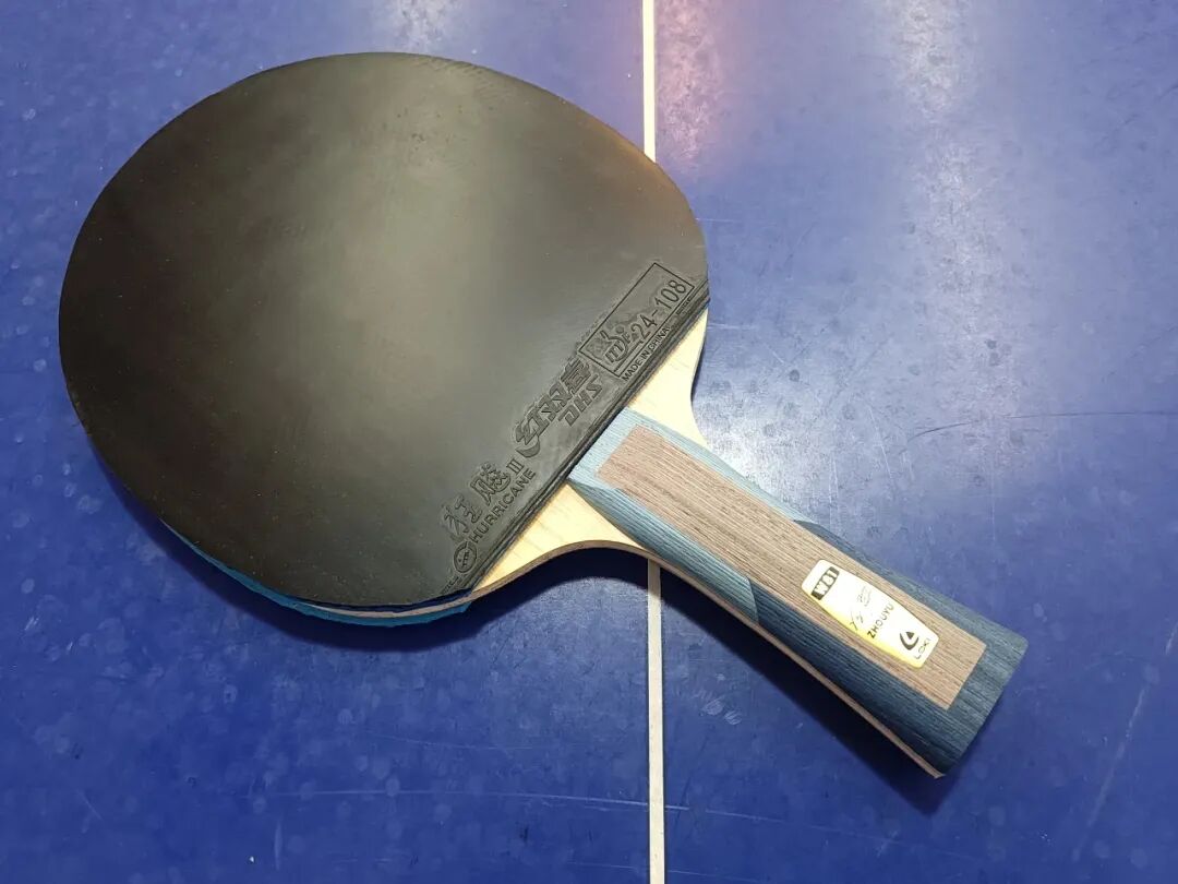 Multiple table tennis rackets laid out on a blue table surface
