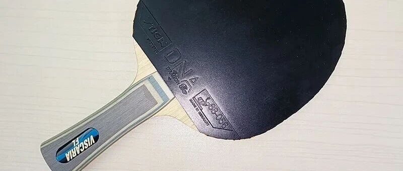 Table tennis paddle assembled with Viscaria blade and a black rubber, placed on a white surface