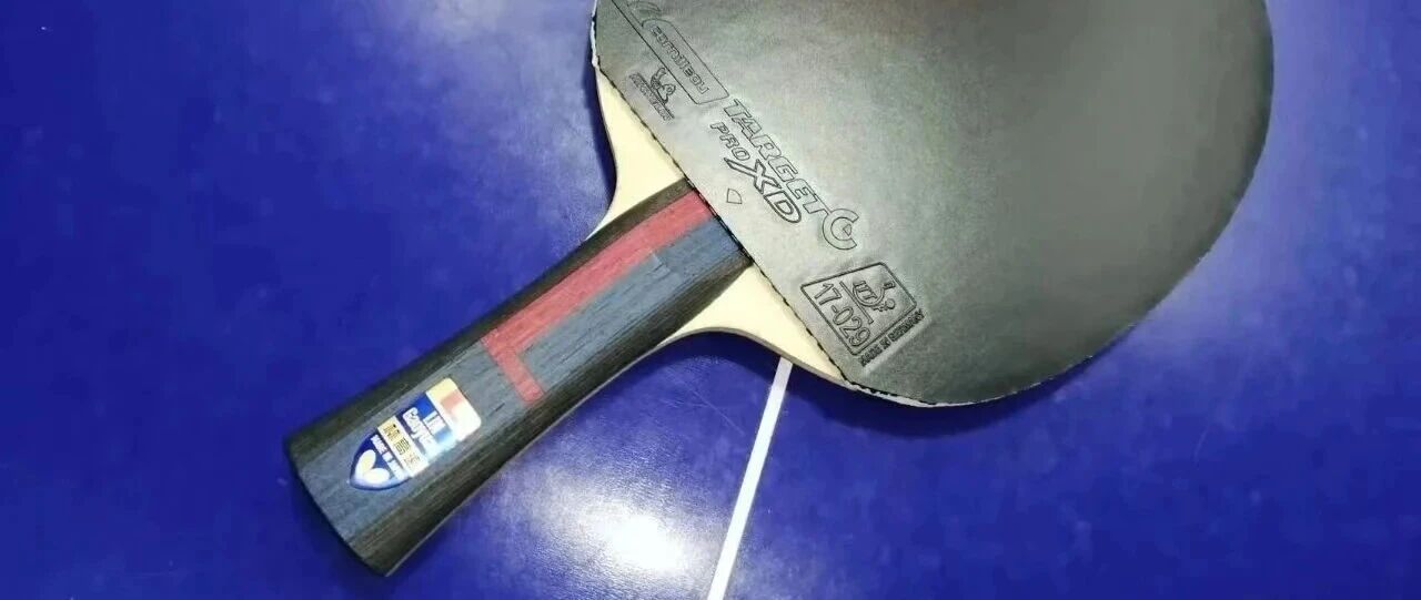 Table tennis paddle with carbon blade on a blue table surface